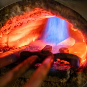 Barres d’acier chauffées au rouge dans le foyer de forge à la flamme, atelier Meignoz Forges & Lames à Romans-sur-Isère (Drôme)
